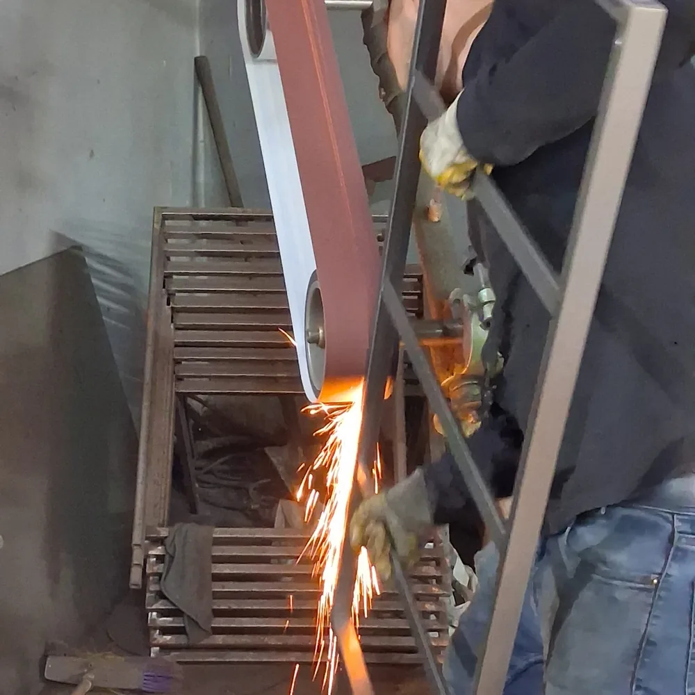 Steel mirror frame held against a belt sander to square the end of a cut