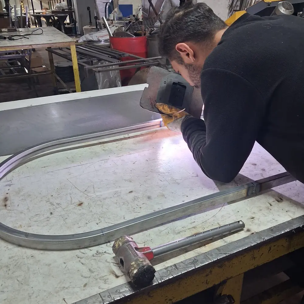 A rolled steel curve being welded on the bench &mdash; how a capsule or round mirror frame is formed